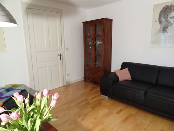 Un salon avec un canapé noir, un meuble en bois et une porte.