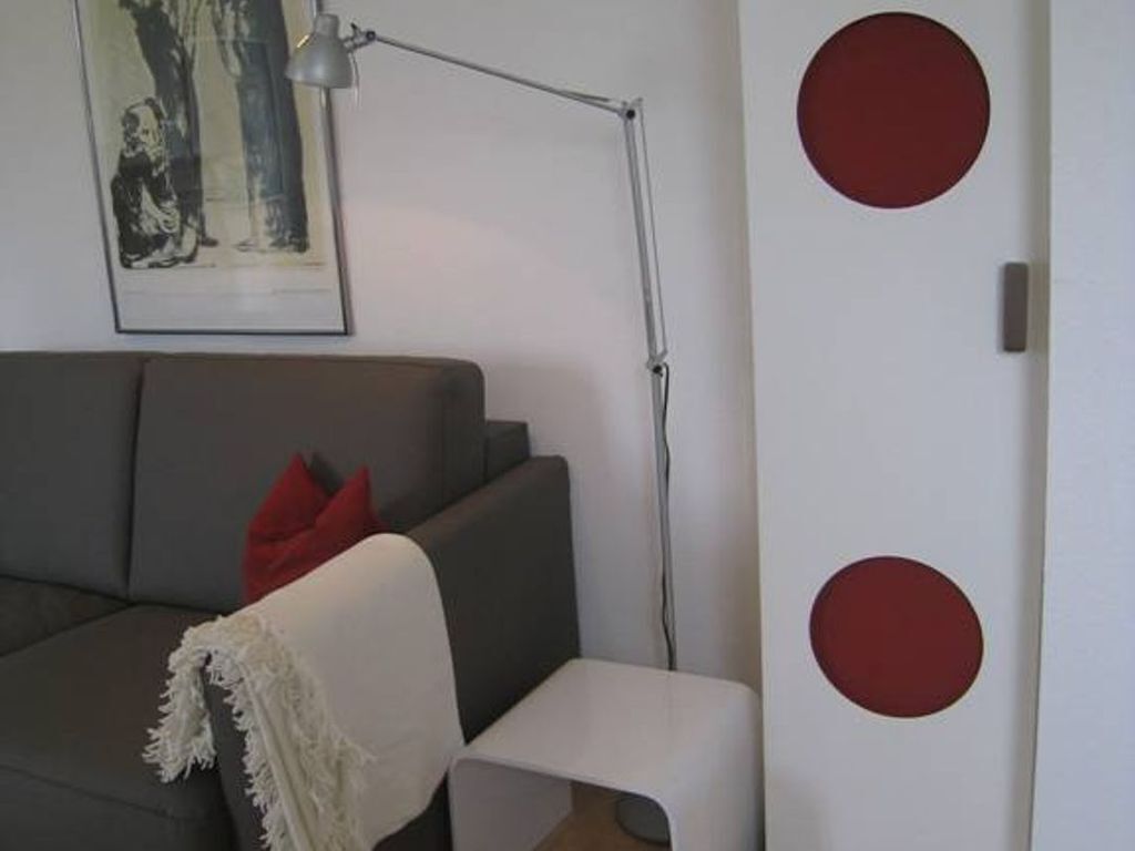 Un salon moderne avec un canapé gris, une petite table d’appoint blanche et un lampadaire.
