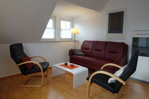 Un salon moderne avec un canapé en cuir rouge, des fauteuils en cuir noir, une table basse en bois et un lampadaire.