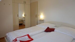 Quarto com cama, guarda-roupa e mesa de cabeceira com abajur.