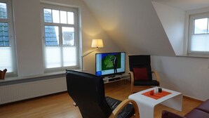 Uma sala de estar moderna com uma TV, um abajur e um sofá.