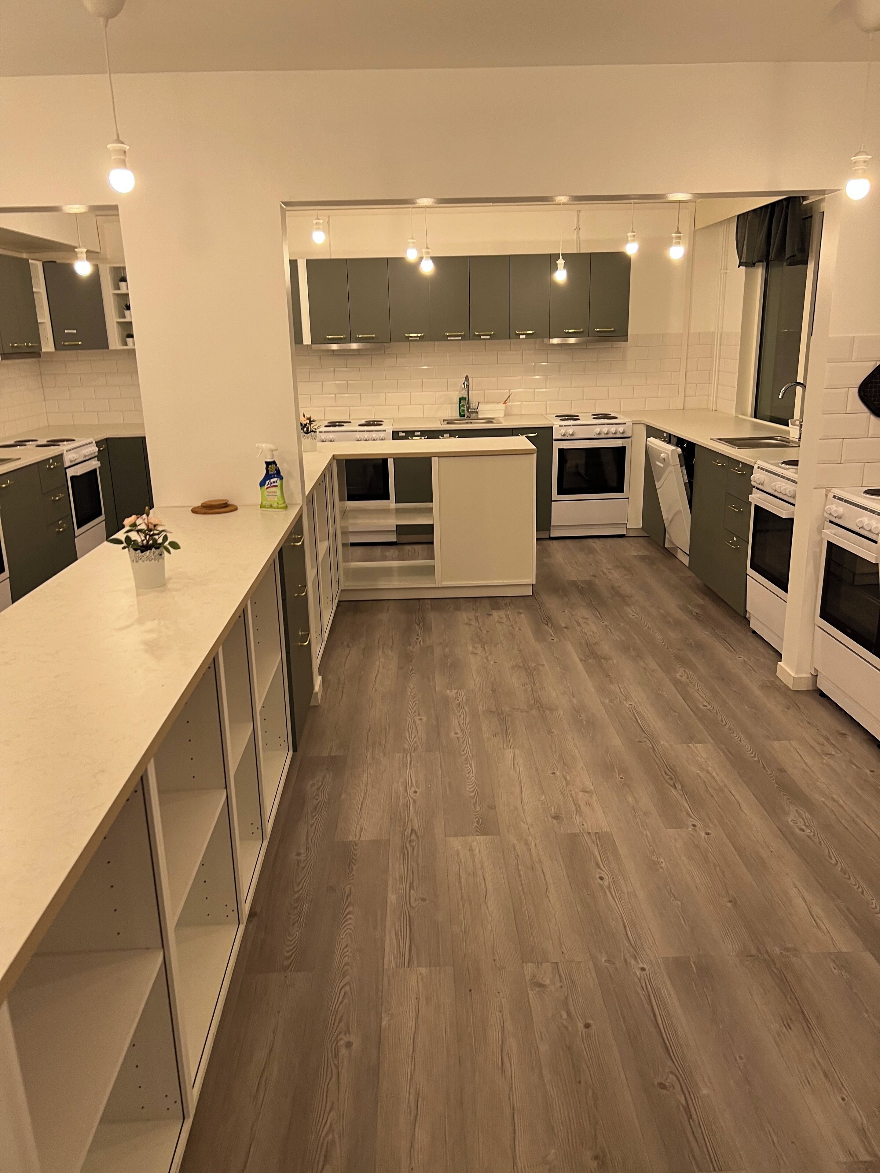 A modern kitchen with white cabinets, a central island, and built-in appliances.