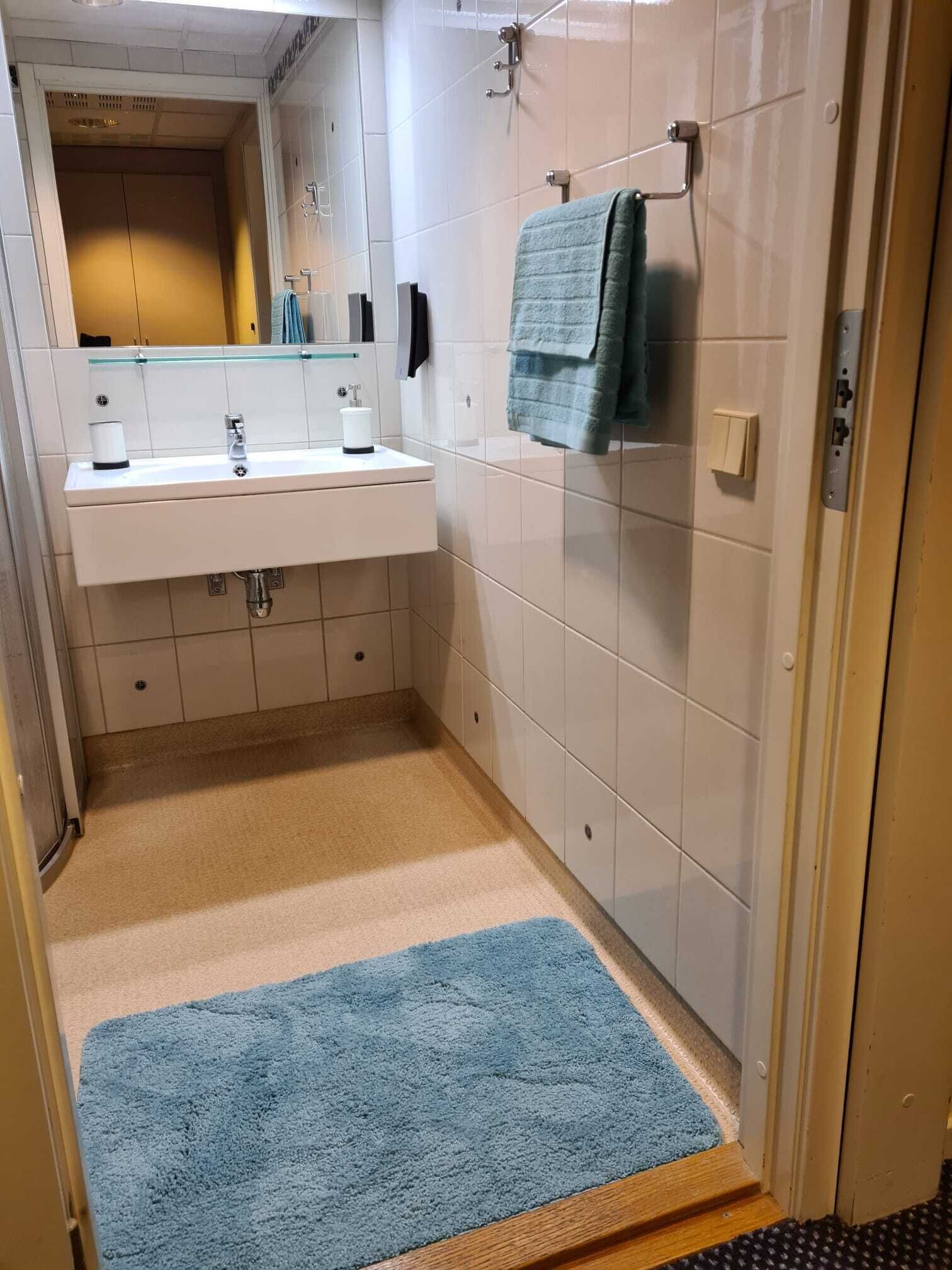 Baño con lavamanos, espejo y toallero blancos.