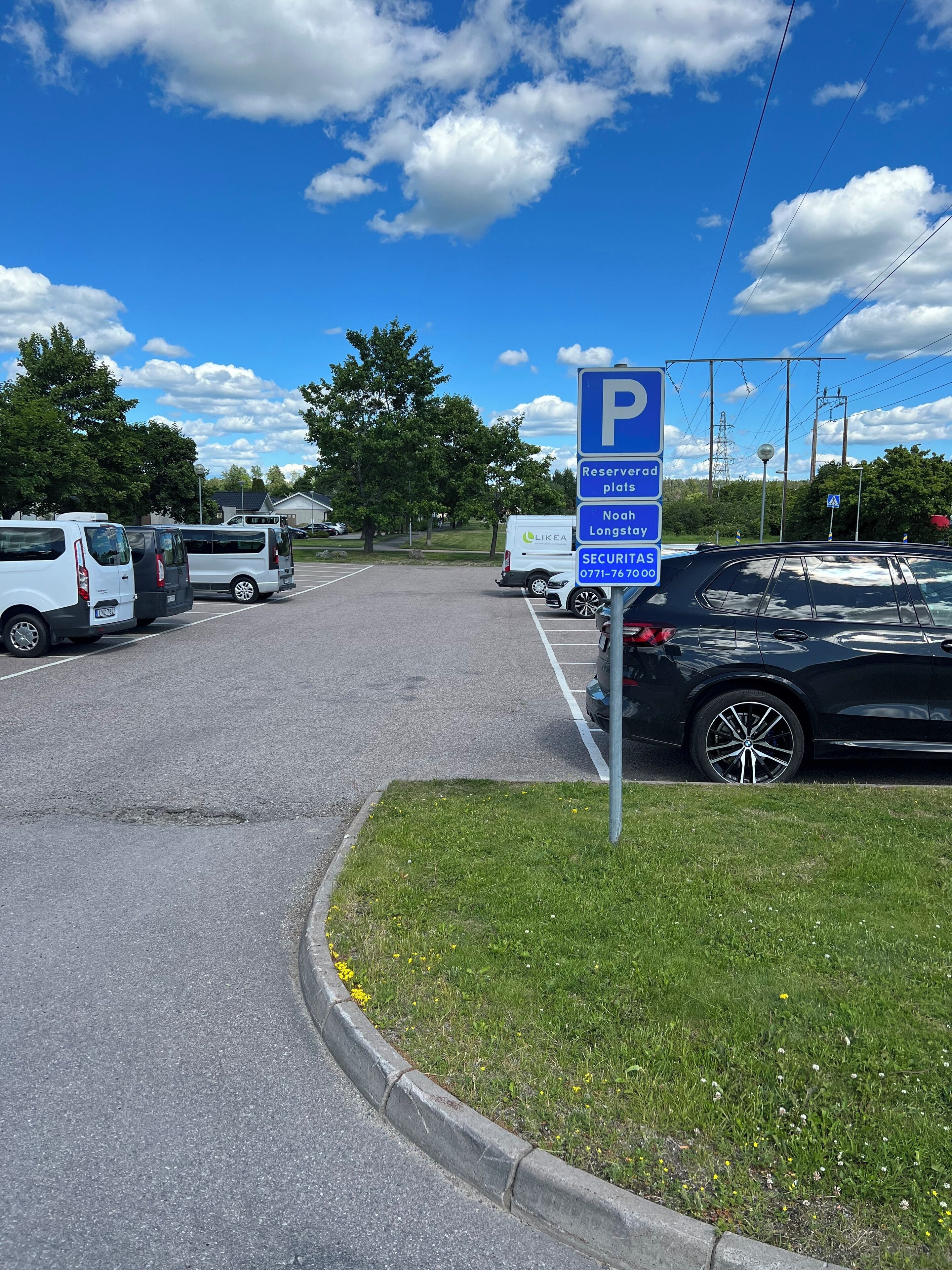 Un estacionamiento con un cartel que indica plazas reservadas para Noah Longstay e información de contacto de seguridad.