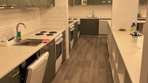 A modern kitchen with grey cabinets, white countertops, and a wooden floor. - Noah Longstay  (Vasteras)