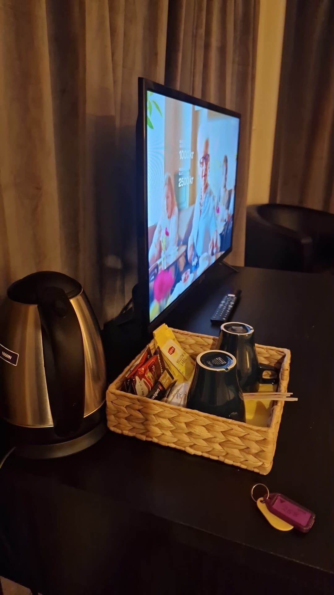 Un televisor sobre una mesa con aperitivos y una tetera.