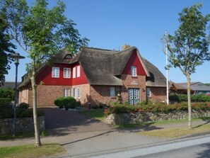 A red brick house with a thatched roof and a stone pathway leading to the entrance. - Vacation at Hüs Dikstian in Alkersum - Hüs Dikstian (Alkersum)