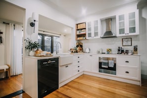 A modern kitchen with white cabinetry, a built-in dishwasher, and a stainless steel oven. - Boutique Cottage in Bacchus Marsh.  Walking distance to town. (Bacchus Marsh)