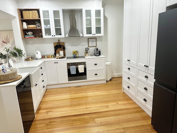 Una cocina moderna con armarios blancos, una campana extractora de acero inoxidable y un refrigerador negro.