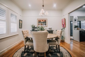 A dining area with a round table, four upholstered chairs, a chandelier, and a framed picture on the wall. - Boutique Cottage in Bacchus Marsh.  Walking distance to town. (Bacchus Marsh)