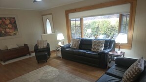 A living room with a dark leather sofa, a wooden bench, and a patterned rug.