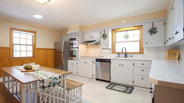 A kitchen with white cabinets, a stainless steel refrigerator, an oven, and a dishwasher.