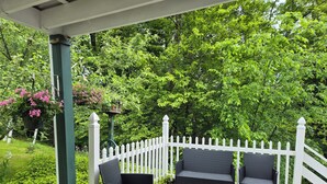 A covered patio with two wicker chairs and a white picket fence.