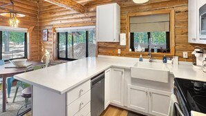 Una cocina moderna con armarios blancos, lavavajillas integrado y un amplio ventanal que proporciona luz natural.