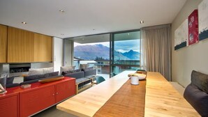 A modern living room with a wooden dining table, red cabinets, and a sofa. - Central Queenstown • 5BR 4.5BA Lake View Getaway (Queenstown)