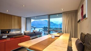 A modern living room with a wooden dining table, red cabinets, and a sofa. - Central Queenstown • 5BR 4.5BA Lake View Getaway (Queenstown)