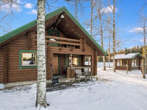 A log cabin with a green roof, a porch with chairs, and a snow-covered ground. - Niittytupa by Interhome (Ruovesi)