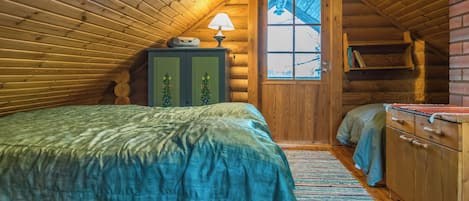 Une chambre confortable dans un chalet en rondins, avec un lit, une commode, une lampe et une fenêtre.