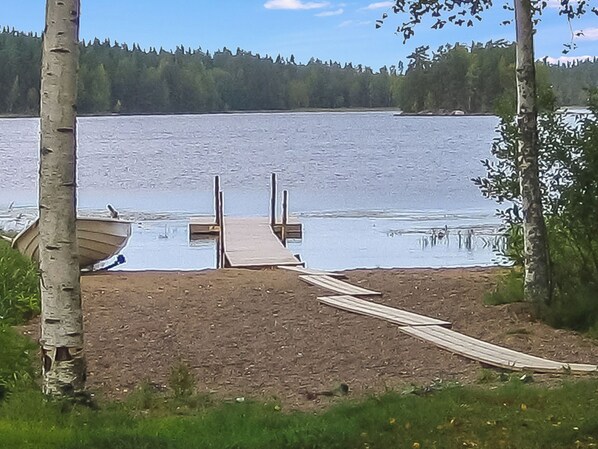 Un pont de fusta que condueix a un llac tranquil amb un vaixell amarrat a la riba.
