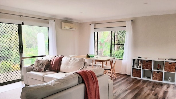 A modern living room with a sofa, a dining table, and a built-in storage unit.