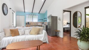 Una sala de estar moderna con un sofá, una mesa de madera y una cocina al fondo.
