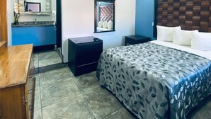 A bedroom with a bed, bedside tables, a desk, and a bathroom with a mirror and sink. - HOTEL LAS VEGAS (Ensenada)