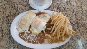 A plate of food with eggs, fries, and rice, and a cup of coffee on a granite countertop. - HOTEL LAS VEGAS (Ensenada)
