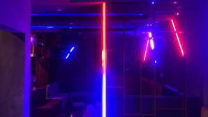A room with a glass partition, a blue and red light installation, and a seating area with a sofa and chairs. - DE EMERITUS COURTYARD HOTEL (Abuja)