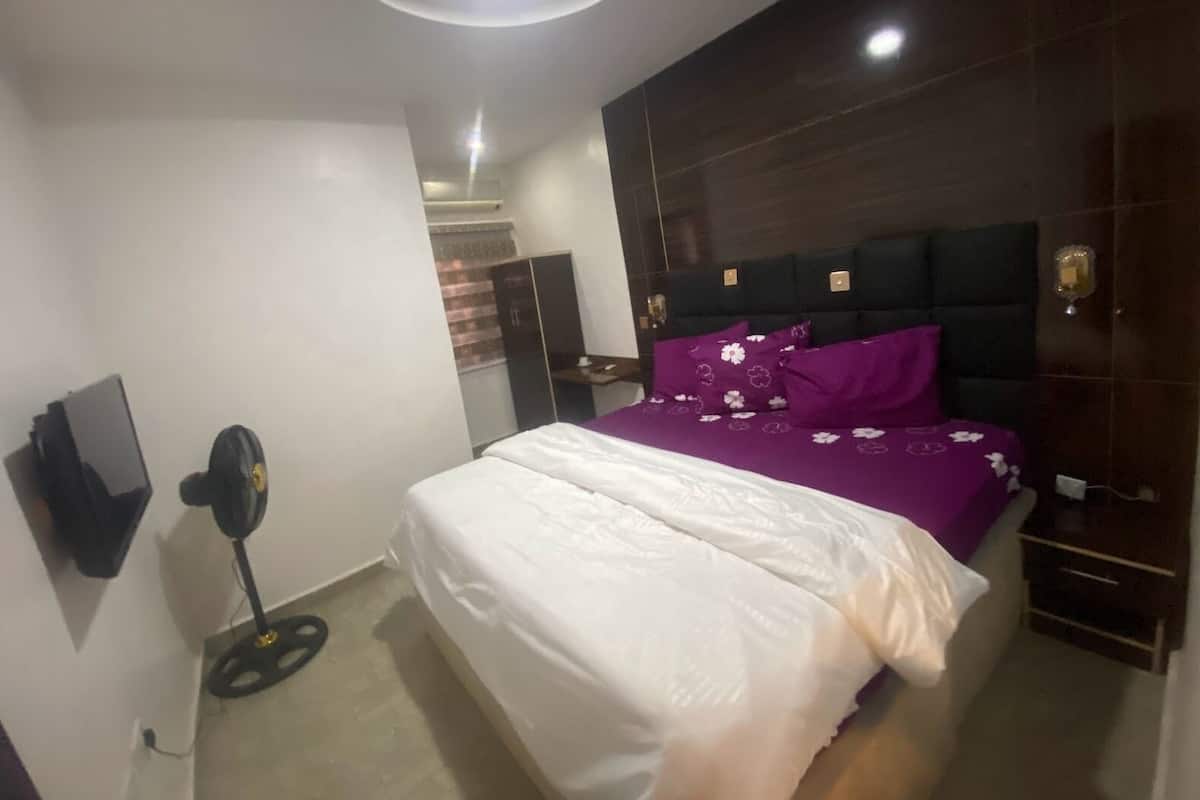 A bedroom with a bed, a wardrobe, a desk, and a ceiling light.