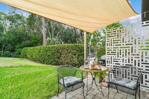 Enjoy al fresco dining on the patio surrounded by a well-maintained lawn and hedge.