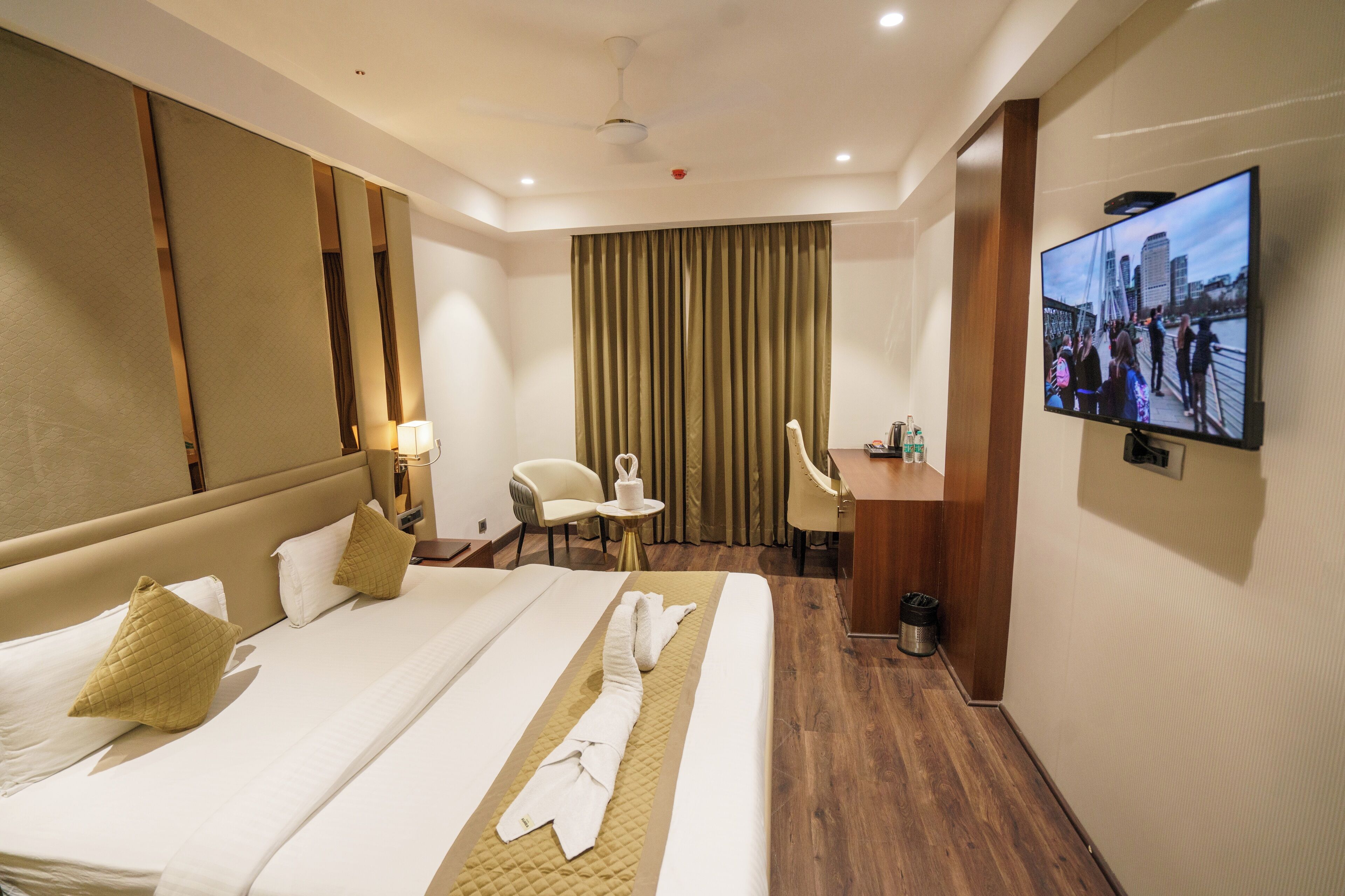 A hotel room with a large bed, a desk, a chair, a television, and a view of a bridge.