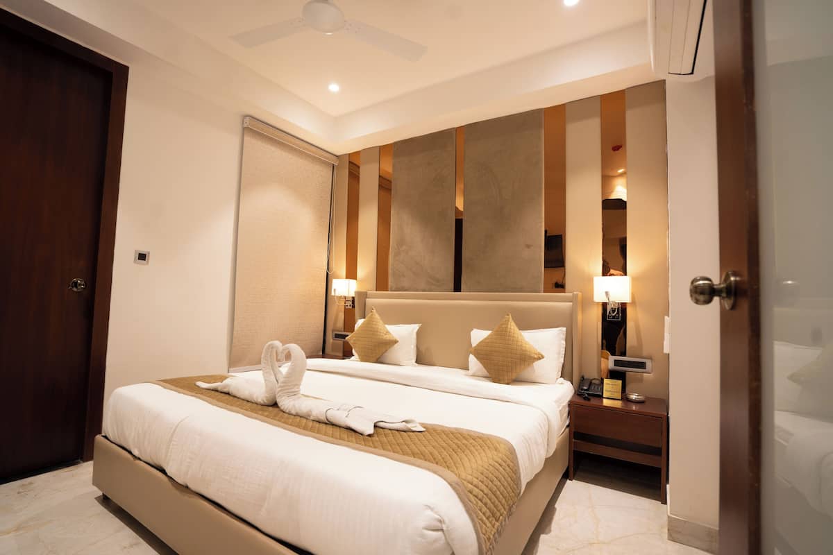 A hotel room with a large bed, a nightstand with a lamp, and a ceiling fan.