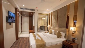 A hotel room with a large bed, a TV mounted on the wall, a mirror, and a nightstand with a lamp. - Aurea by The Wallflower Hotels (Kota)
