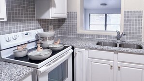A kitchen with white cabinets, a stove, a sink, and a window with blinds. - Charming 3-bedroom house in delightful Jacksonville with AC, WiFi (Jacksonville)