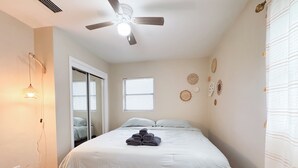 A bedroom with a bed, a ceiling fan, a window, and a door leading to another room. - Charming 3-bedroom house in delightful Jacksonville with AC, WiFi (Jacksonville)