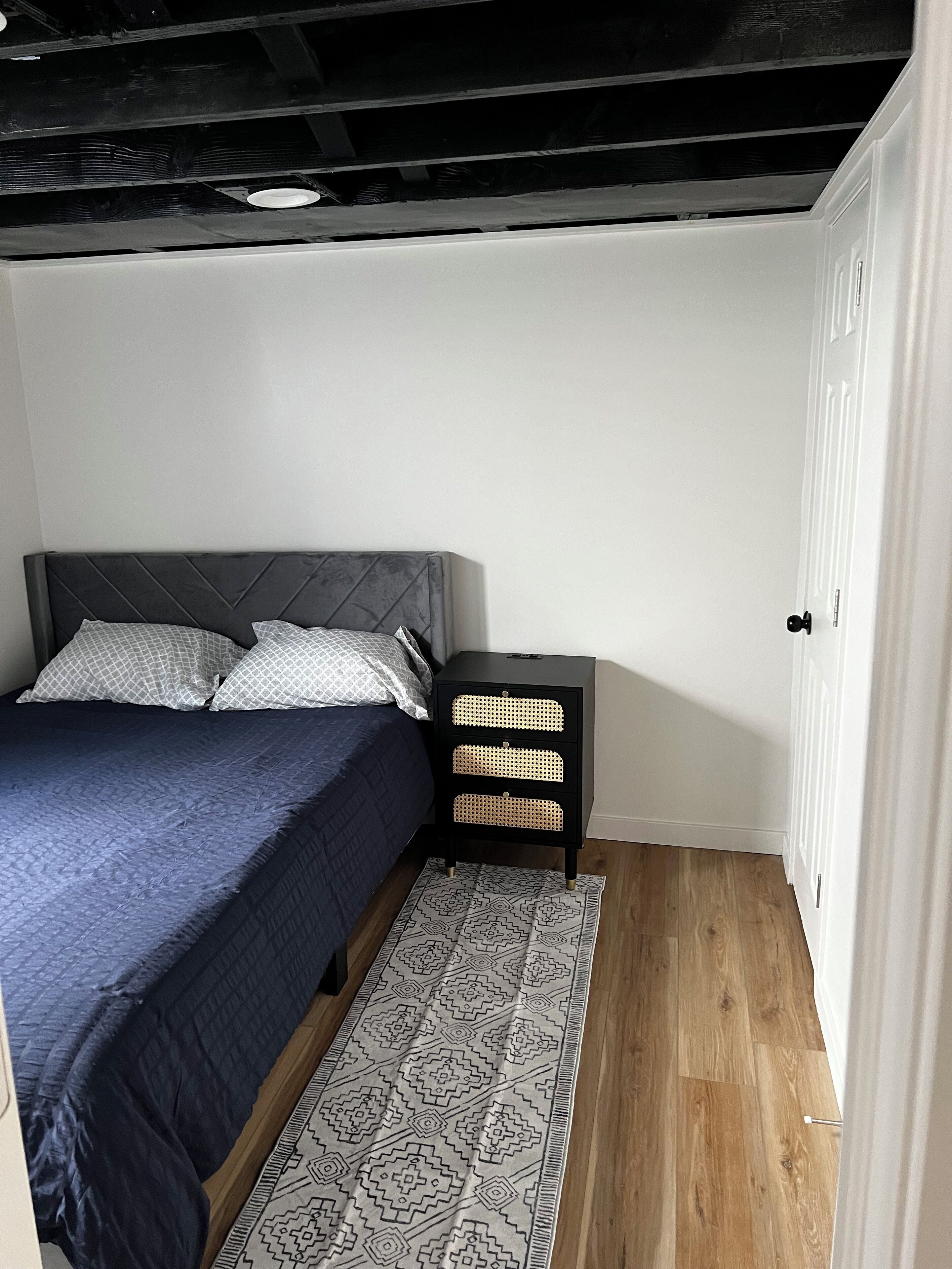 Une chambre à coucher avec un lit, une table de chevet, un tapis à motifs et un plancher en bois.