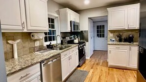 A modern kitchen with white cabinets, granite countertops, stainless steel appliances, and wooden flooring. - Luxurious large estate house in beautiful Alexandria! (Alexandria)
