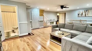 A spacious living area with a wooden floor, a grey sectional sofa, and a ceiling fan. - Luxurious large estate house in beautiful Alexandria! (Alexandria)