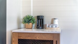 A coffee maker, a potted plant, and a coffee pod box on a countertop.