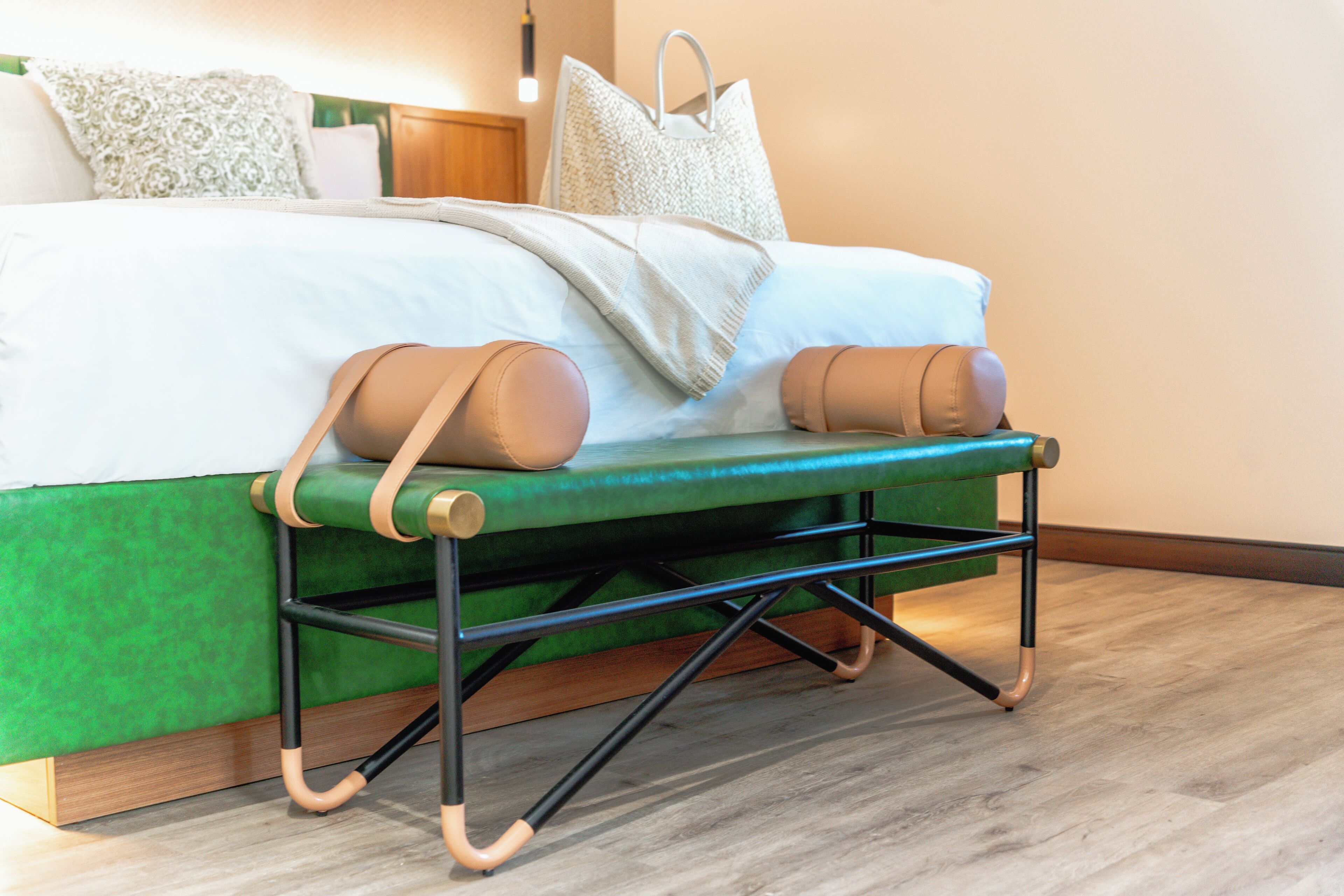 A bed with a green upholstered headboard, a wooden floor, and a white pillow.