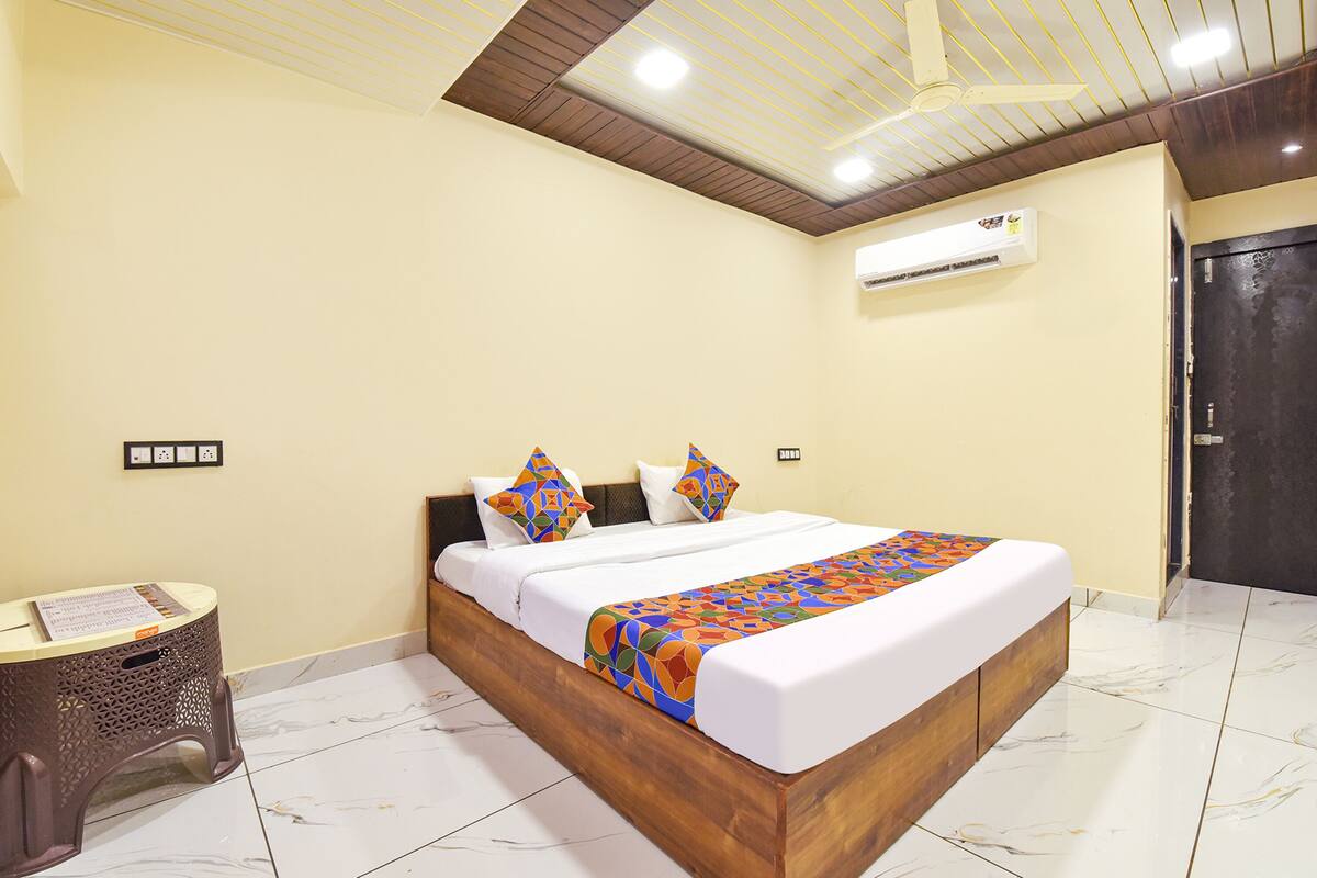 A hotel room with a large bed, wooden headboard, white bedding, and a ceiling fan.
