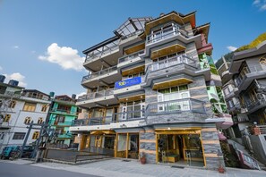 A multi-story hotel with balconies, a sign for 'fabHOTELS', and a ground-level entrance. - Fabhotel Rigzin Nest Cottage (Manali)
