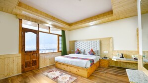 Ein Schlafzimmer mit Holzboden, einem großen Bett mit gepolstertem Kopfteil, einem Schreibtisch und Blick durch ein Fenster.
