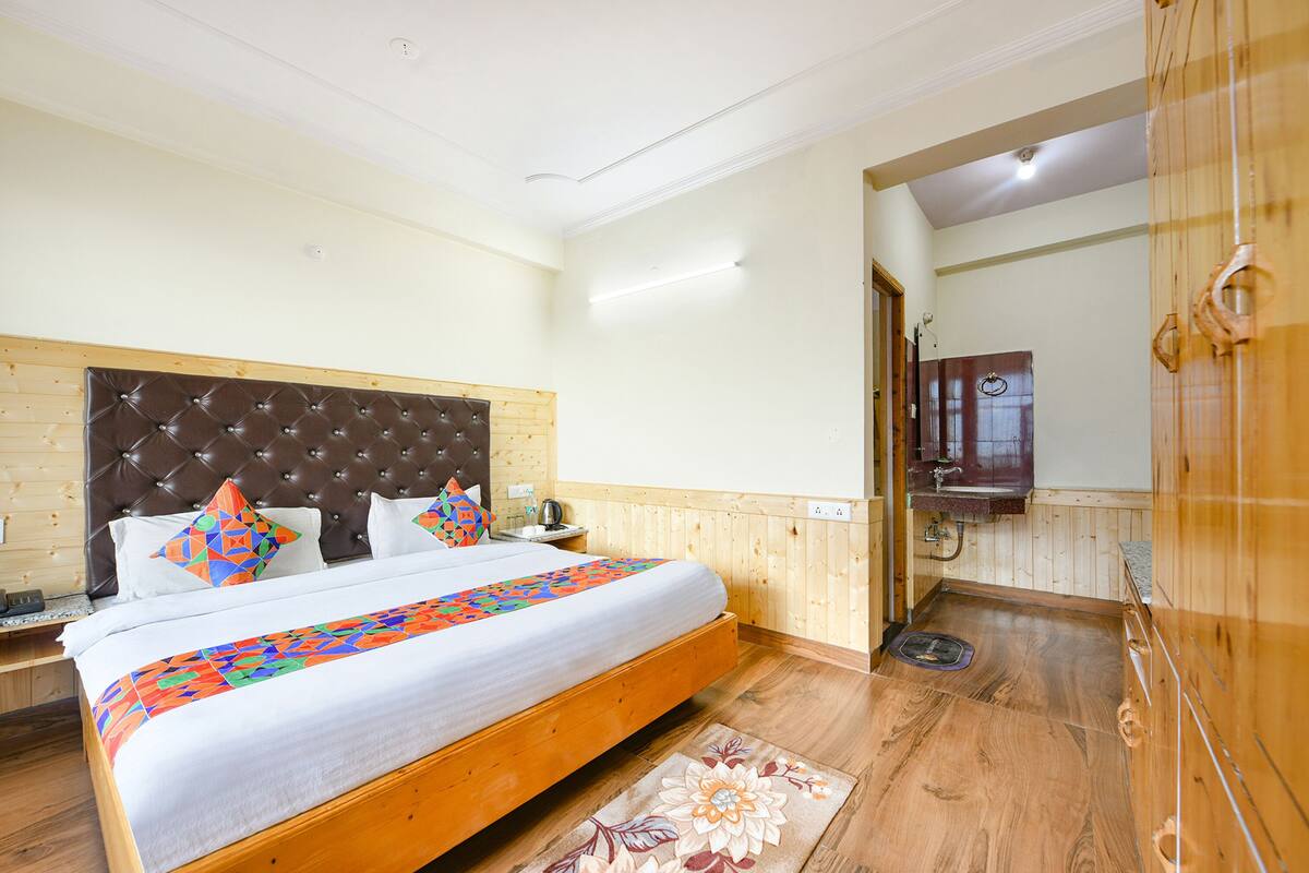A large bed with a wooden headboard, a bedside table, and a colorful bedspread.