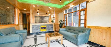 A hotel lobby with wooden walls, a reception desk, and two sofas.