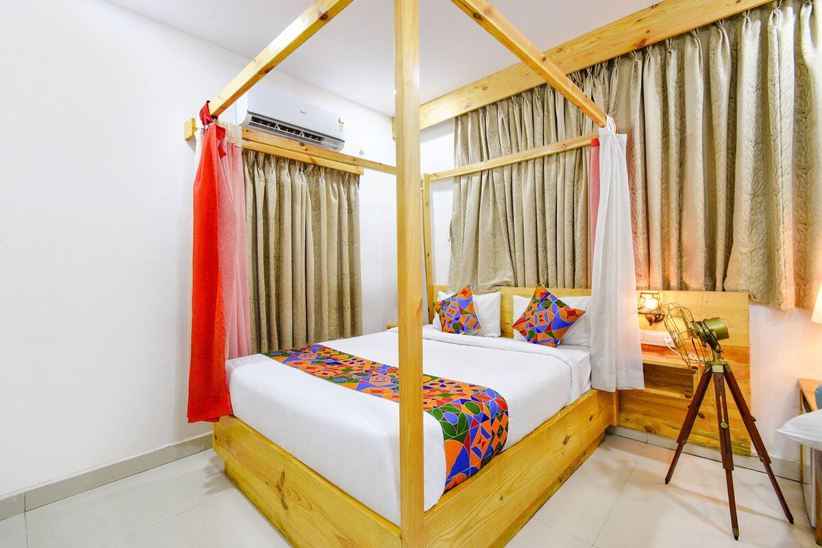 A four-poster bed with a geometric-patterned bedspread, a wooden headboard, and a bedside table with a lamp.