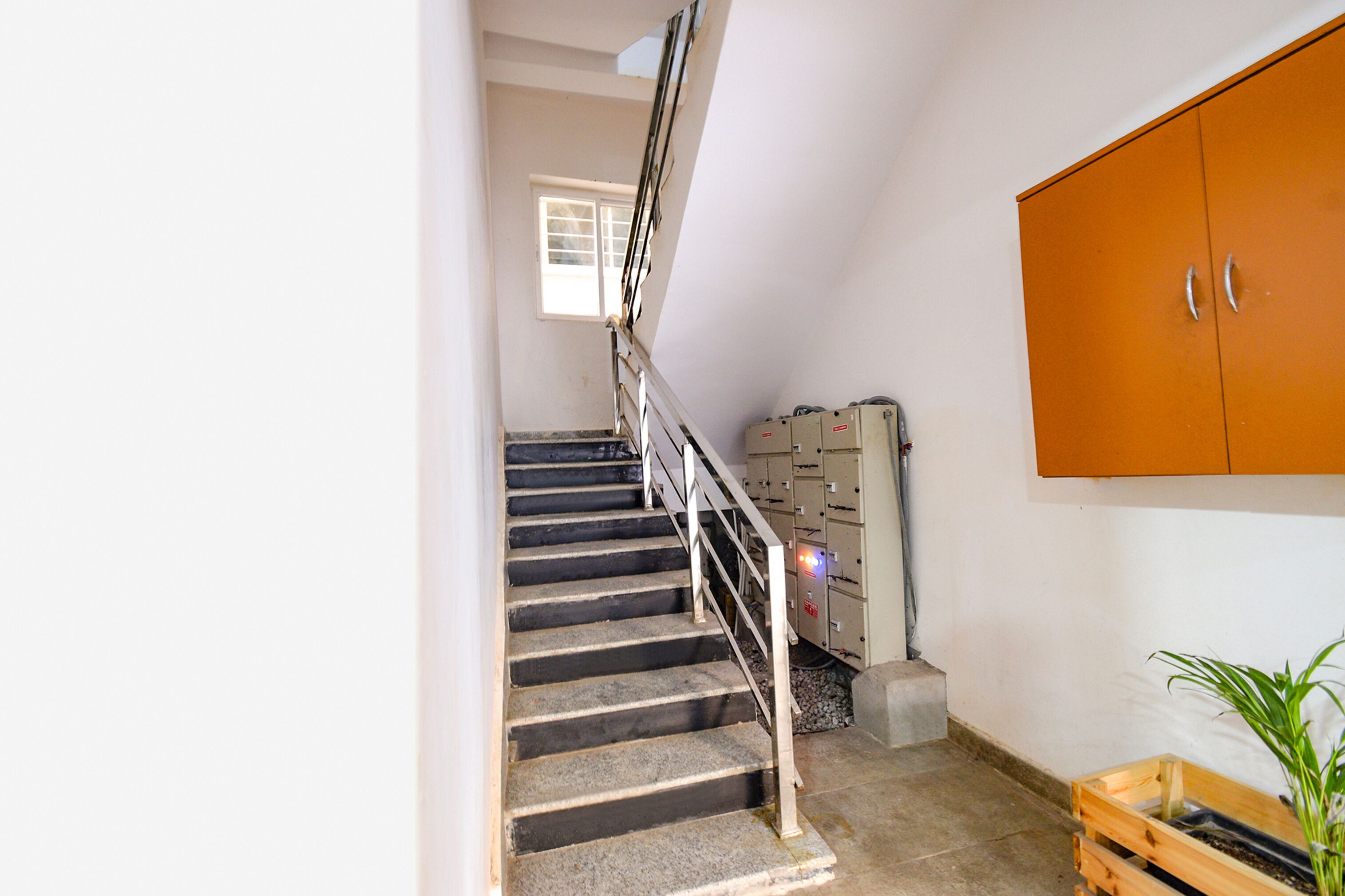 A staircase with a metal railing, a wooden cabinet, and a window.