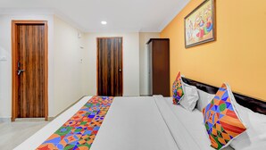 A hotel room with a bed, a wooden door, a painting on the wall, and a colorful runner on the floor. - FabHotel Hitek N - Nr. Sindhu Hospital and HITEX EXHIBITION CENTER, Hitech City (Hyderabad)