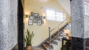Un escalier avec une rampe, une petite table avec une lampe et une plante en pot.