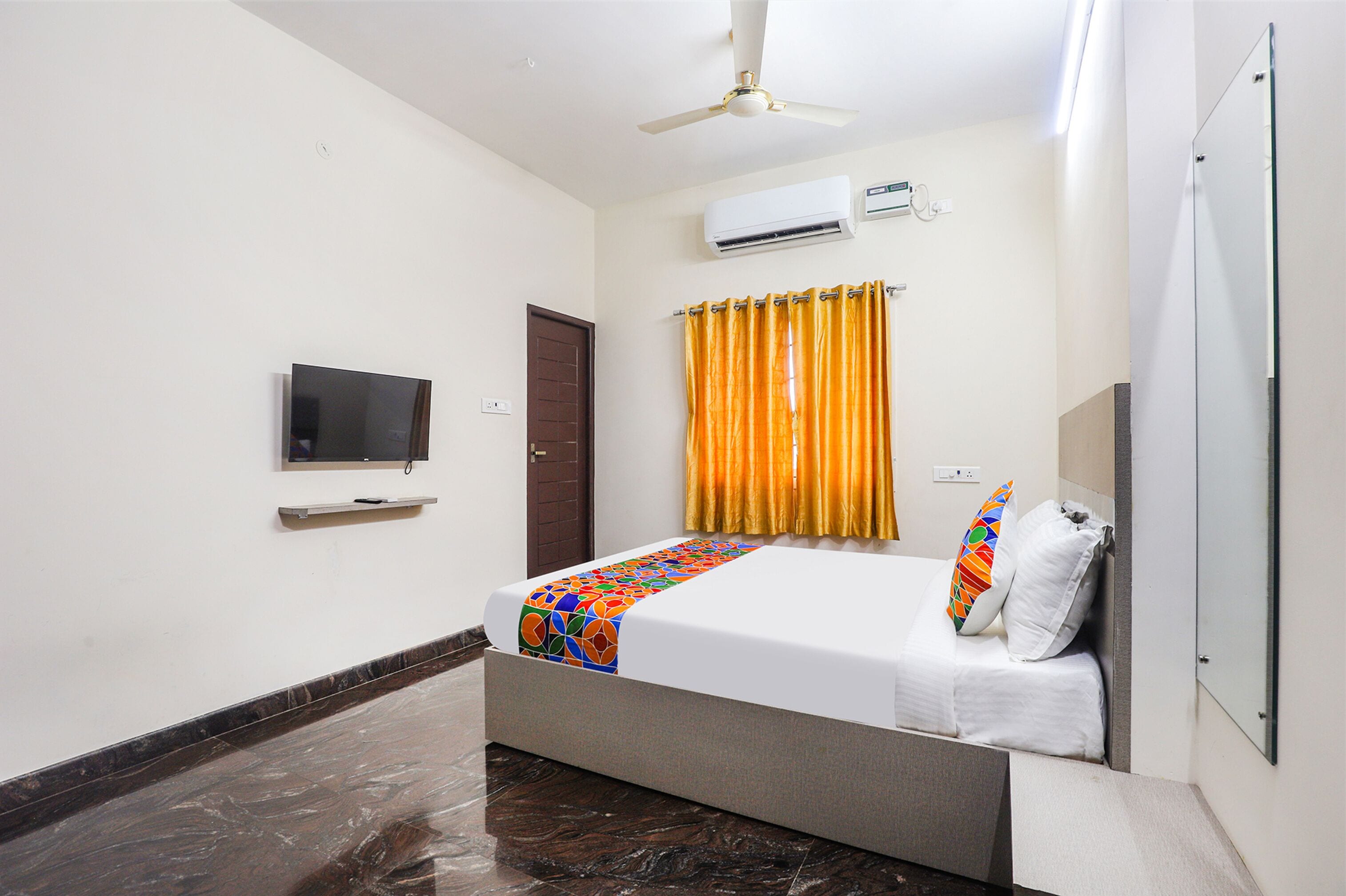 A hotel room with a bed, a television, an air conditioning unit, and a shower area.